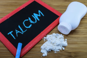 talcum written on chalkboard with baby talcum powder and container on wood background