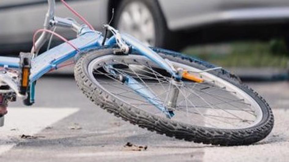 una bicicleta tirada en el pavimento después de un accidente con un automóvil.
