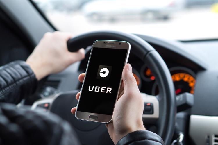 un conductor abriendo la aplicación uber dentro de su automóvil